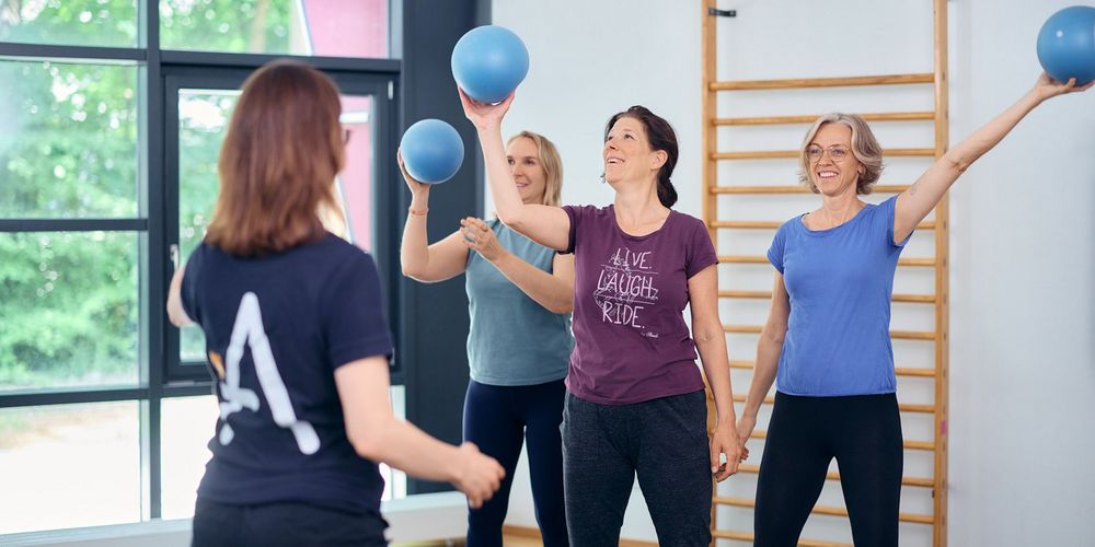 Teilnehmerinnen beim Rehasport mit Gymnastikbällen unter professioneller Anleitung im Therapie- und Trainingszentrum in Neuss.