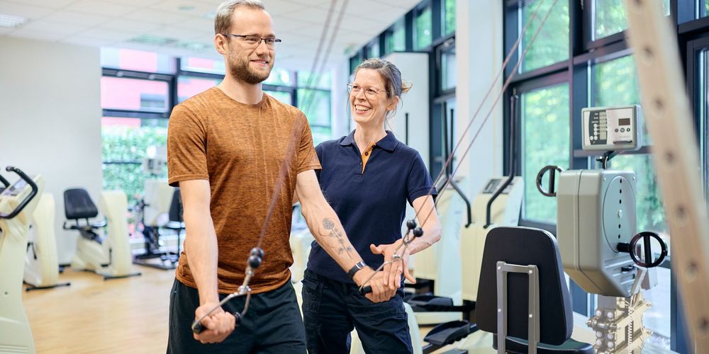 Sporttherapeutin begleitet einen Teilnehmer beim Gerätetraining im Rahmen der psychologischen Sporttherapie im TTZ in Neuss.